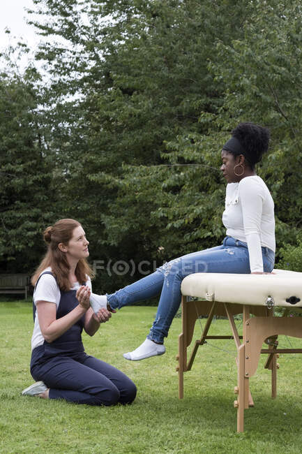 Terapeuta tocando um cliente pés, uma sessão de terapia ao ar livre — Fotografia de Stock