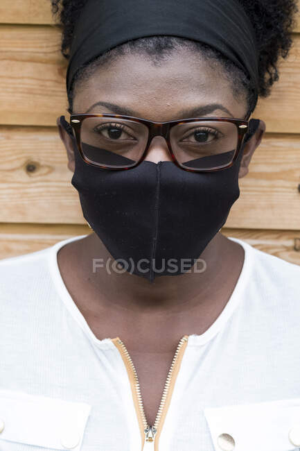 Портрет черной женщины в очках и маске, смотрящей в камеру. — стоковое фото