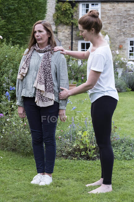 Therapist focusing on the standing posture of a client in a garden. — Stock Photo