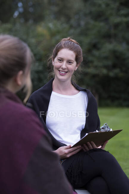 Woman and female therapist seated talking in a garden — Stock Photo