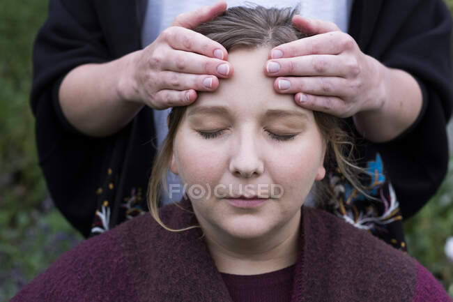 Terapeuta usando ambas as mãos tocando o topo de uma cabeça de cliente. — Fotografia de Stock
