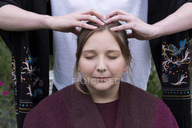 Terapista con entrambe le mani che toccano la parte superiore della testa di un cliente. — Foto stock