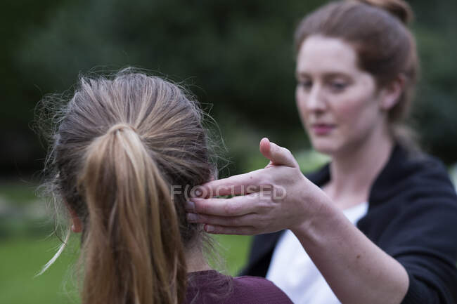Una terapeuta tocando la cabeza de un cliente por su oreja. - foto de stock