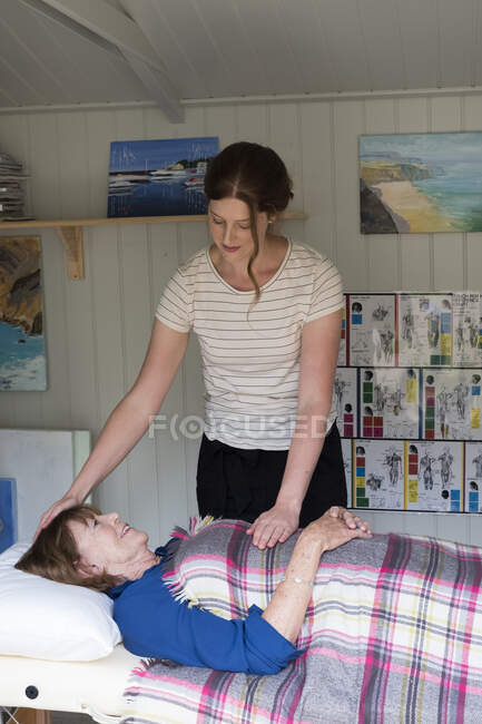 Mujer en un sofá un terapeuta que pone las manos en la cabeza y el estómago - foto de stock