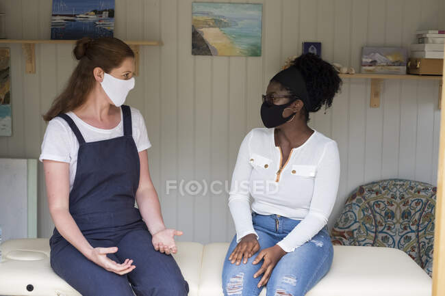 Mujer y terapeuta en mascarillas en una sesión de terapia - foto de stock