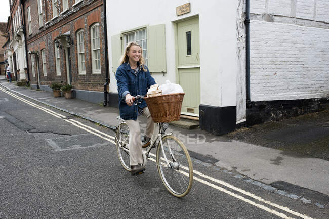 Jeune femme blonde faisant du vélo dans une rue du village. — Photo de stock