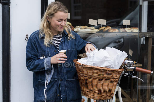 Молода блондинка стоїть поруч з велосипедом за межами магазину без сміття . — стокове фото