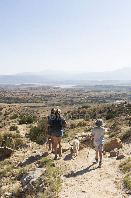 Tres personas, caminatas familiares en un sendero a través de un paisaje protegido del cañón - foto de stock