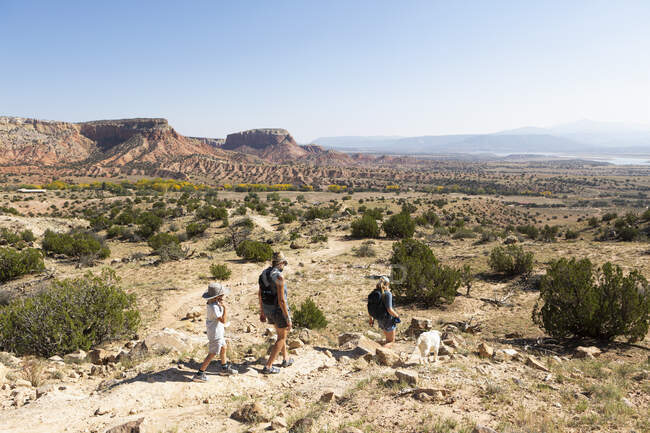 Three people, family hiking on a trail through a protected canyon landscape — Stock Photo