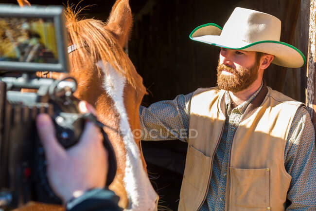 Vaquero con caballo siendo filmado en rancho, Colombia Británica, Canadá. - foto de stock
