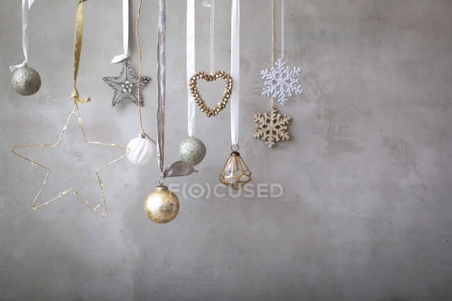 Рождественские украшения, серебряные, белые и золотые безделушки на лентах на сером фоне. — стоковое фото