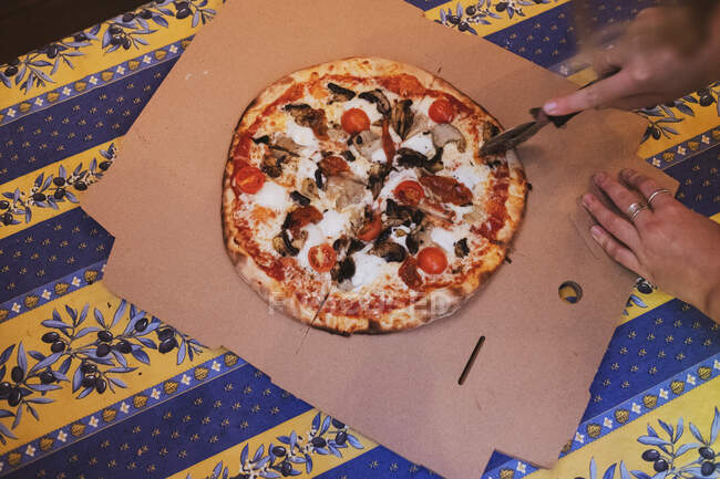 Высокоугольный крупный план режущей пиццы с помощью колеса пиццы. — стоковое фото
