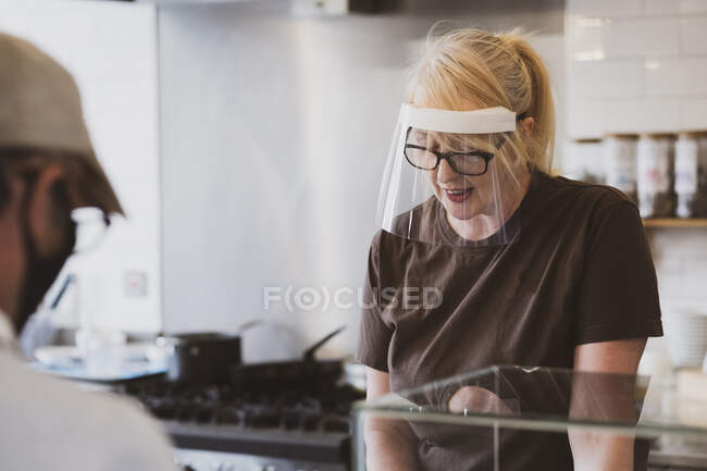 Blond waitress wearing face mask working in a cafe. — Stock Photo