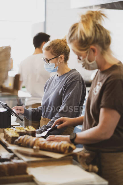 Blond waitress wearing face mask working in a cafe, preparing food. — Stock Photo