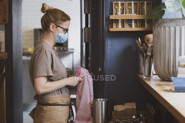 Serveuse blonde portant un masque facial travaillant dans un café. — Photo de stock