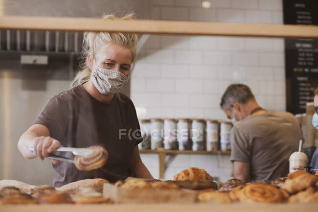 Блондинка офіціантка в масці для обличчя, що працює в кафе . — стокове фото