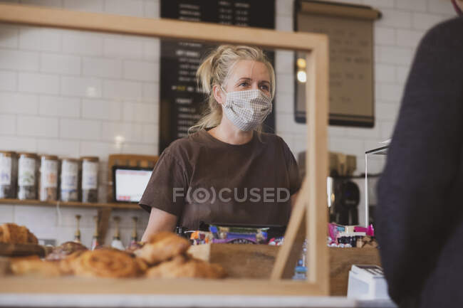 Cameriera bionda con la maschera facciale che lavora in un caffè. — Foto stock