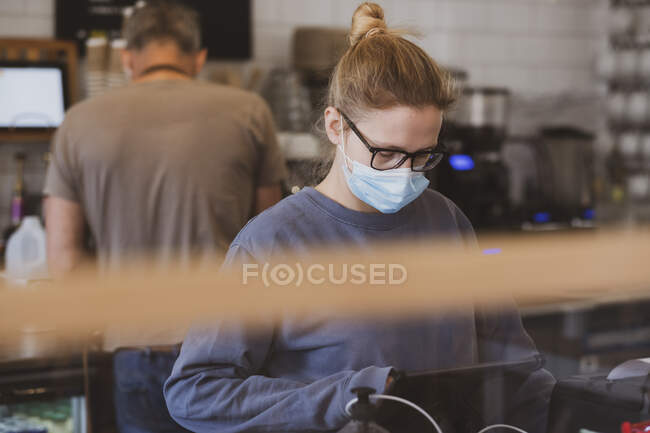 Біла офіціантка в масці на обличчі працює в кафе.. — стокове фото