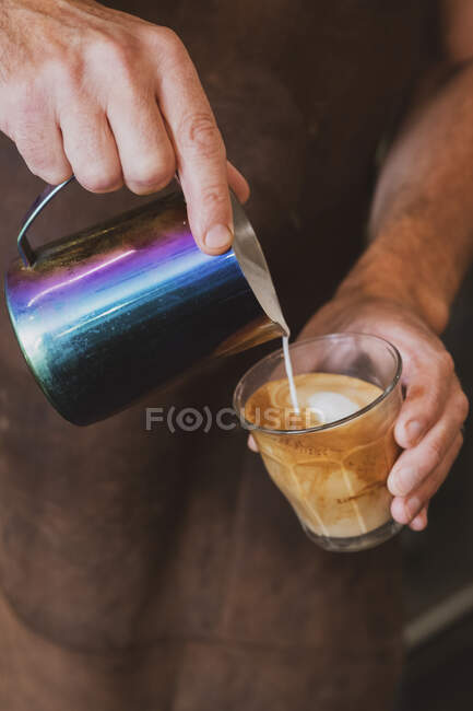 Primer plano de barista vertiendo un café con leche. - foto de stock