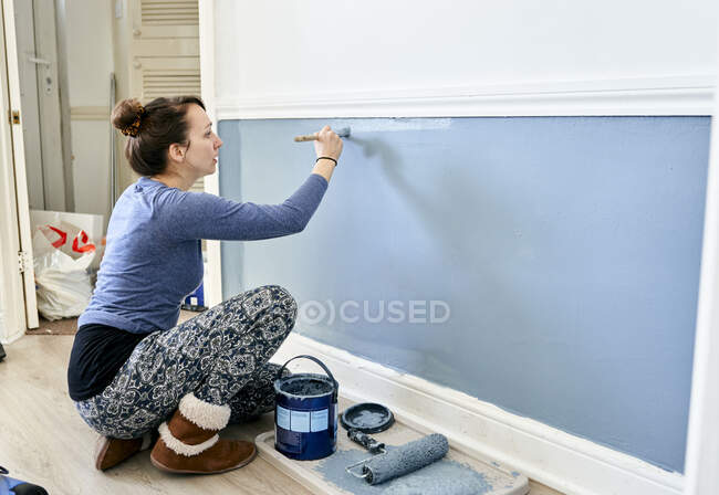Frau bemalt Wand zu Hause. — Stockfoto