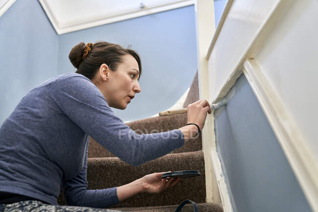 Женщина рисует лестницу дома — стоковое фото
