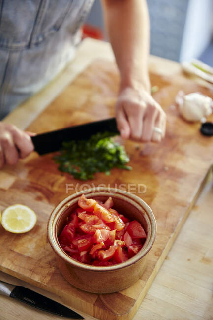 Tiro cortado de mulher cortando manjericão para salada de tomate — Fotografia de Stock