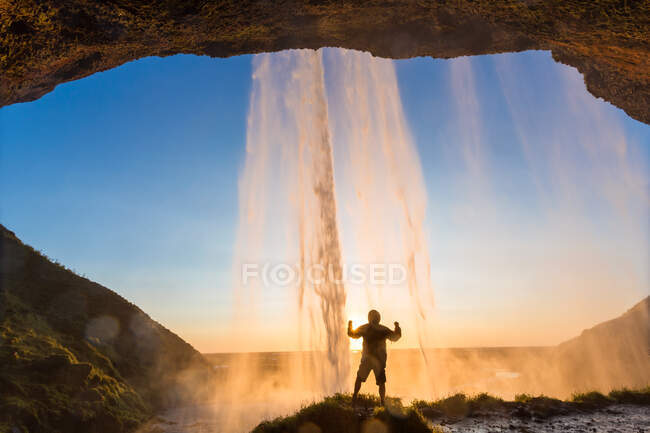 Hombre detrás de Seljalandsfoss Waterfall, Islandia del Sur, Islandia - foto de stock