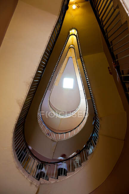 Pessoas ascendendo uma escada em espiral, vista de baixo. — Fotografia de Stock