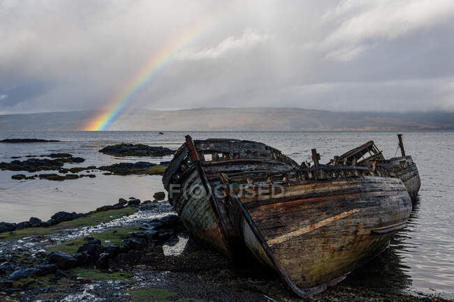 Rainbow and beached old wooden fishing boats on shore at Salen — Stock Photo
