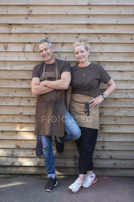 Homem e mulher de avental, colegas fazendo uma pausa do trabalho, rindo — Fotografia de Stock