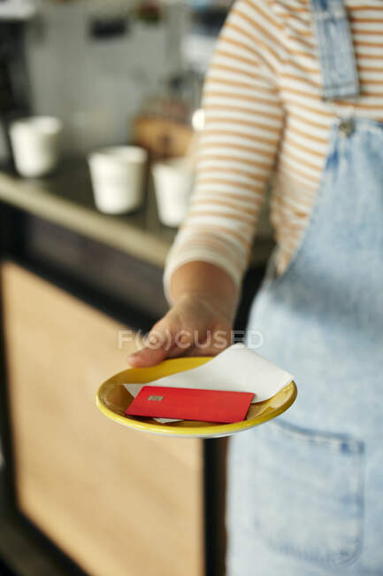 Café garçonete segurando prato com conta e cartão de crédito. — Fotografia de Stock