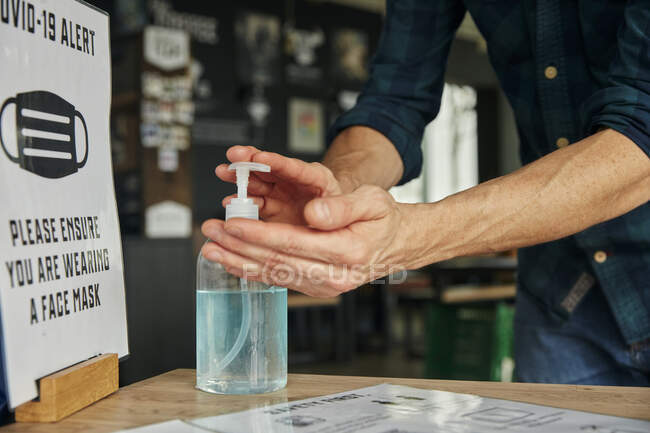 Man using hand sanitizer gel in restaurant — Stock Photo