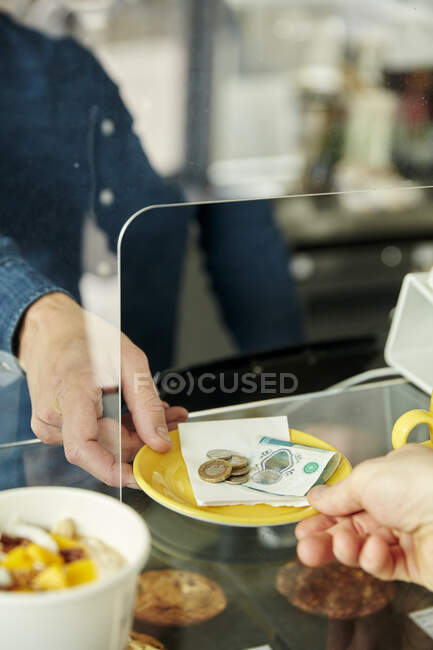 Gros plan des mains échangeant la plaque avec de l'argent pour le paiement dans le café — Photo de stock