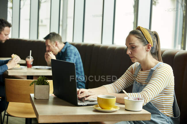Donna seduta in un caffè con un computer portatile — Foto stock