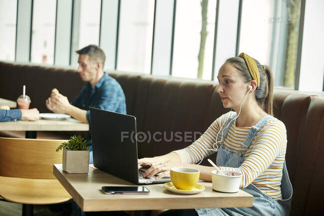 Mulher sentada em um café usando um laptop — Fotografia de Stock