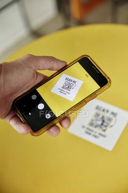 Persona che utilizza uno smartphone, fotografa una traccia e traccia il codice QR su uno sfondo giallo — Foto stock