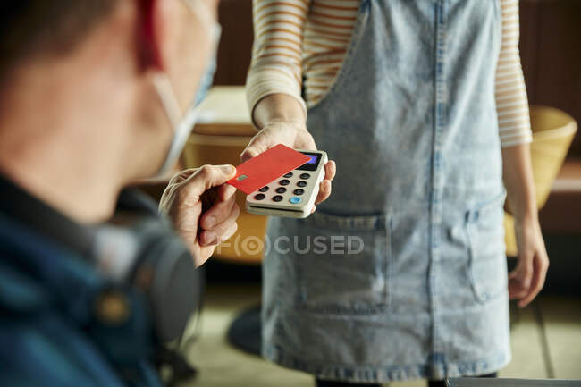 Mulher segurando terminal de pagamento sem contato para um cliente pagando com cartão — Fotografia de Stock