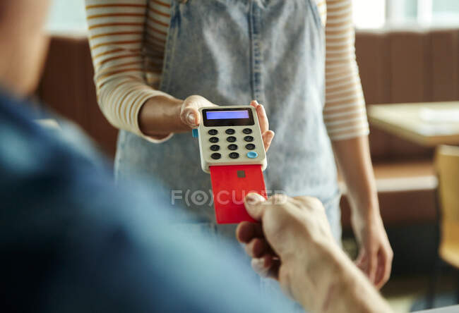 Жінка тримає безконтактний платіжний термінал для клієнта, який платить карткою — стокове фото