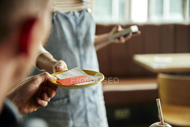 Frau hält kontaktloses Zahlungsterminal für Kunden, die mit Karte bezahlen — Stockfoto