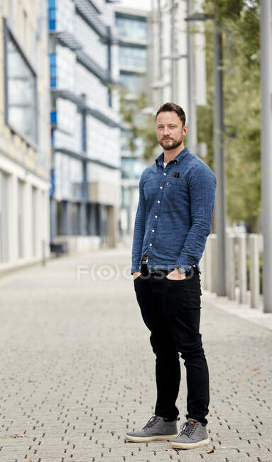 Man with a beard standing outdoors in a city on a quiet street — Stock Photo