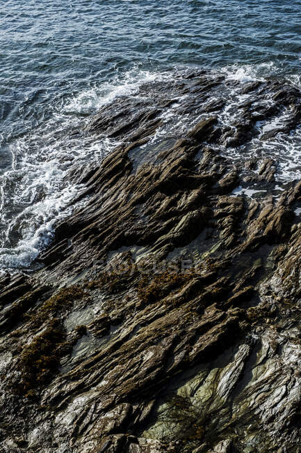 Vista ad alto angolo di onde che si lavano intorno a una riva rocciosa. — Foto stock