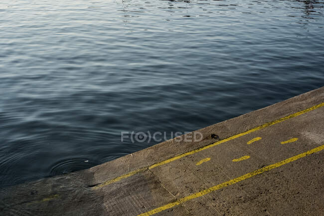Alto angolo primo piano di orme gialle e linee dipinte su asfalto in un porto. — Foto stock