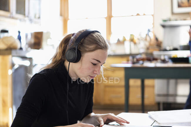 Teenage girl wearing headphones, drawing on paper — Stock Photo