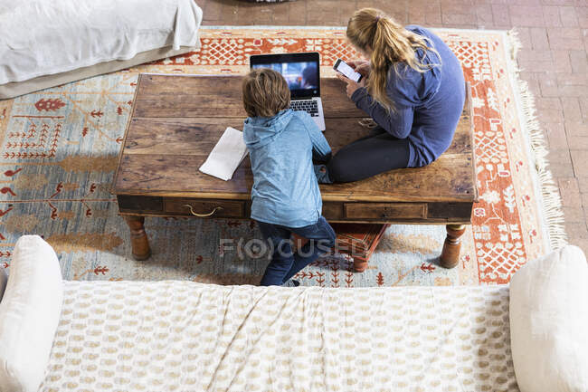 Menina adolescente e seu irmão mais novo usando laptop e telefone inteligente — Fotografia de Stock
