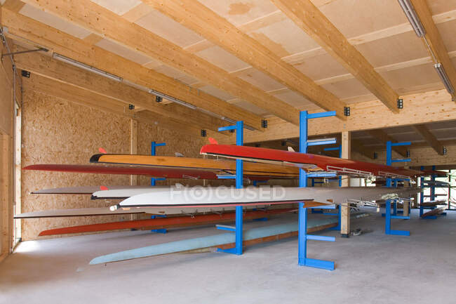 Escovas de remo ou barcos armazenados em prateleiras na casa de barcos. — Fotografia de Stock