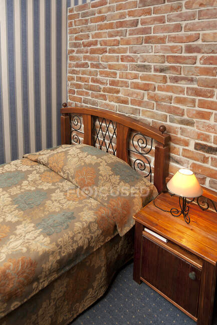 Bed in bedroom with wallpaper and brick wall. — Stock Photo