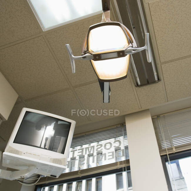 Vista de ángulo bajo de la luz del dentista y monitor de computadora montado en la pared. - foto de stock