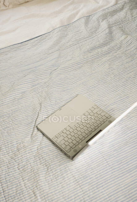 Overhead view of open laptop on bed. — Stock Photo