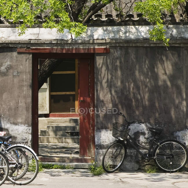 Bicicletas apoyadas en la pared exterior del patio de la casa. - foto de stock
