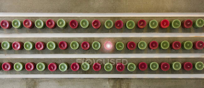 Overhead view of red and green candles lined up, one lit. — Stock Photo